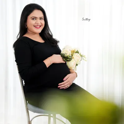 A classic and bright indoor portrait. The simple black dress, paired with a bouquet of white roses, creates a look of timeless elegance and joy.