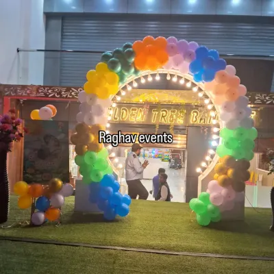 A vibrant, multi-colored balloon arch at the entrance of a banquet hall. This arch is lit up and creates a welcoming and festive atmosphere for guests as they arrive.