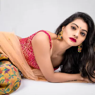A vibrant portrait of a model in a colorful lehenga, lying down and looking directly at the camera. This shot captures the rich colors and textures of Indian ethnic wear in a relaxed, contemporary pose.