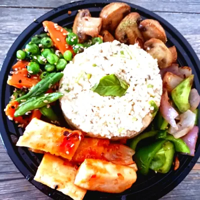 A balanced and wholesome millet bowl, perfect for a healthy lunch. It features a serving of fluffy millet surrounded by sautéed mushrooms, glazed tofu, and fresh, crisp vegetables.