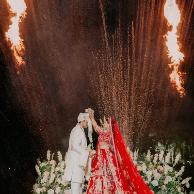 A spectacular varmala moment for Sakshi and Ayush, framed by dramatic fire pyrotechnics. We excel at capturing these peak moments with precision and artistry.