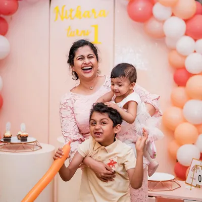 A mother's joyful laugh with her two children during a first birthday party. We capture the real, chaotic, and beautiful moments that define family celebrations.