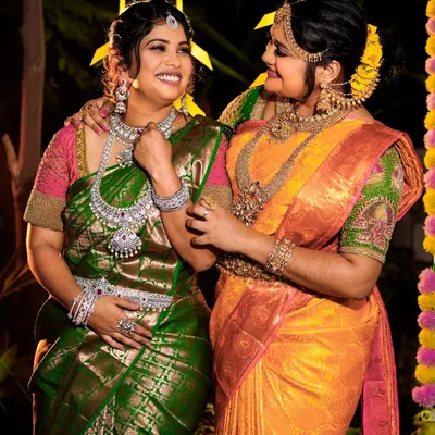 A perfect example of coordinating bride and bridesmaid looks. The bride wears a grand temple set while her bridesmaid shines in a modern American Diamond set, both available for rent.