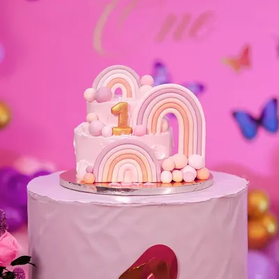 A beautiful two-tiered cake for a first birthday, decorated with pastel rainbows and delicate butterflies. This cake was the centerpiece of a whimsical and elegant celebration.