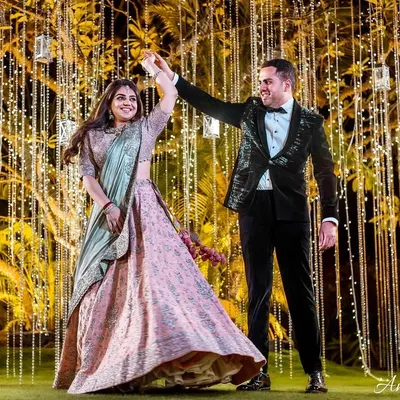 A perfect twirl against a backdrop of cascading fairy lights. This shot captures the bride's joy and the beautiful movement of her lehenga during a sangeet night performance.