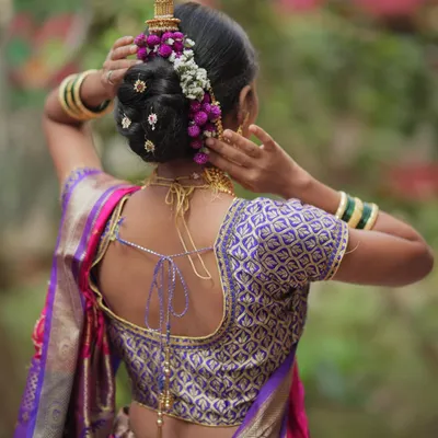 A beautiful view of a traditional Maharashtrian bridal bun, or khopa, adorned with delicate flowers and hair accessories. This is a classic style we teach in our hairstyling module.