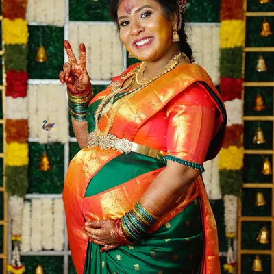 A happy mother-to-be at her Valaikappu ceremony, dressed in a traditional silk saree. This shot captures her excitement for the new arrival.