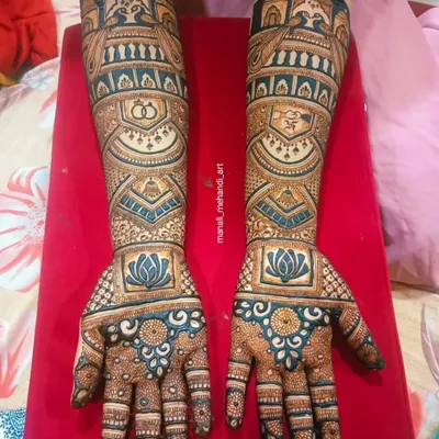 This bridal design uses a striking combination of dark and light shading. The bold lotus and architectural elements are filled with fine lines, while the teal-colored glitter adds a modern touch for the photo.
