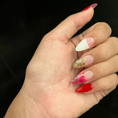 An example of our creative nail artistry, combining a French tip, glitter, delicate floral painting, and a bold solid red. This set shows the range of techniques our artists can use in a single, cohesive design.