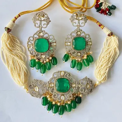 A truly exclusive Victorian-style bridal set in a silver and gold finish with high-quality emerald green stones. This set, including the choker and matching long earrings, is perfect for a grand reception look.