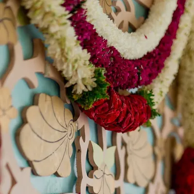 A close-up of a custom-carved backdrop with a traditional floral garland. This highlights our team's skill in creating bespoke decor elements.