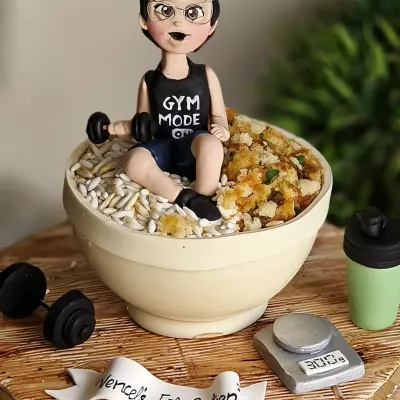 This cake was made for a true gym freak whose mom wanted to celebrate his discipline. It's a cake replica of his daily meal prep bowl of keema and rice, complete with a hand-sculpted figurine of him in "Gym Mode," tiny dumbbells, and a food scale.