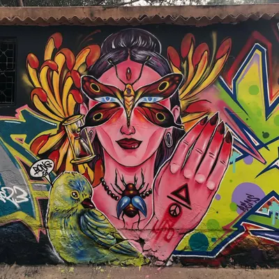 A detailed view of the figurative portion of a mural. This character features a butterfly mask and is surrounded by symbolic elements like an hourglass, showcasing a more illustrative and mystical side of my spray paint art.