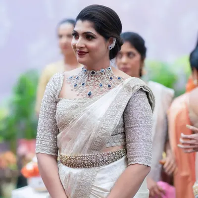A beautiful and elegant look for a wedding guest. The makeup is sophisticated, with a bold lip and defined eyes that complement her stunning white and silver saree.
