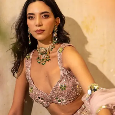 A beautiful shot from a campaign for Surabhi Chopra Label. The model wears a delicate pink lehenga with mirror work, styled with a contrasting emerald necklace for a fresh, summery feel.