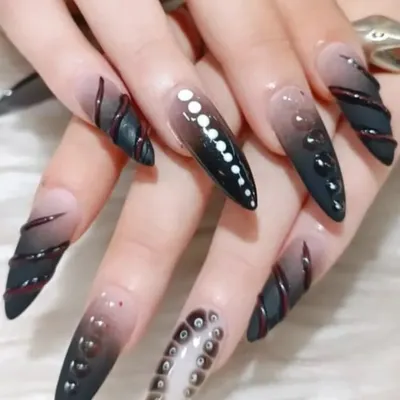 For those who love avant-garde designs, this set features extra-long stiletto nails with a black ombre base and intricate 3D textures and patterns.
