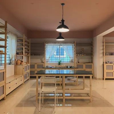 The main workspace of our studio, with custom built tables and shelves waiting to be filled with your creations. We designed it with natural wood and warm tones to feel open and welcoming, with plenty of natural light for you to work by during the day.