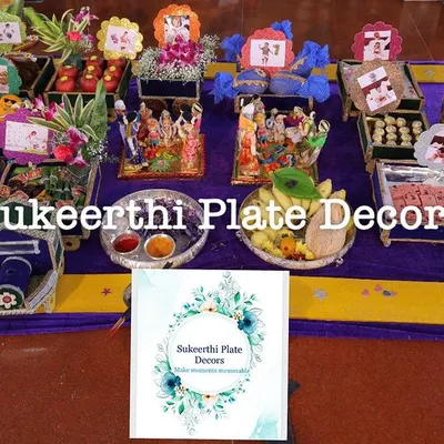 A large and colourful display of decorated plates and gift items for an ear piercing ceremony, featuring a variety of traditional elements.