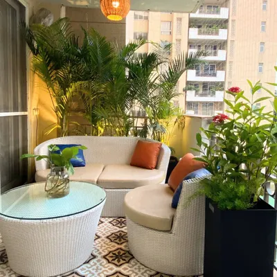 This cozy seating arrangement at our Palm Springs project features a curved outdoor sofa that fits perfectly into the balcony corner. The vibrant cushions add a pop of color against the neutral wicker and lush green backdrop.