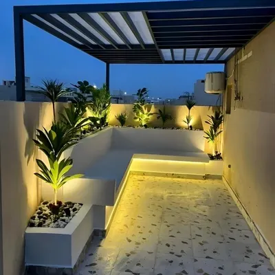 The same terrace project viewed at dusk, showcasing the impact of our lighting design. Strategically placed uplights and strip lighting highlight the plants and architectural features, creating a warm and inviting ambiance for evening use.