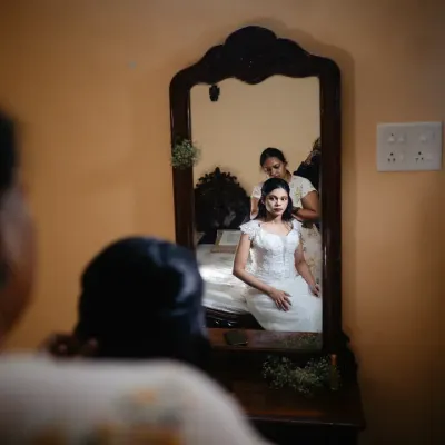 A quiet moment of reflection for the bride as she gets her hair done, seen through the frame of a vintage mirror.