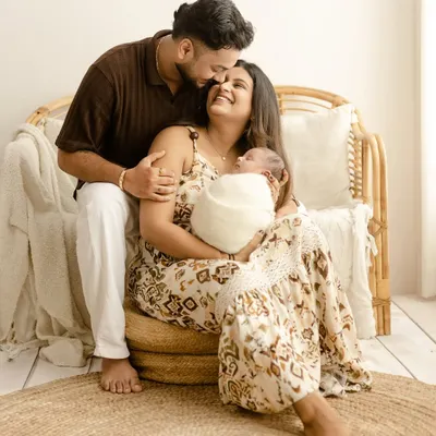 A beautiful family portrait with a newborn. The parents look on with so much love as the mother cradles their sleeping baby, perfectly capturing the joy of the first few days.