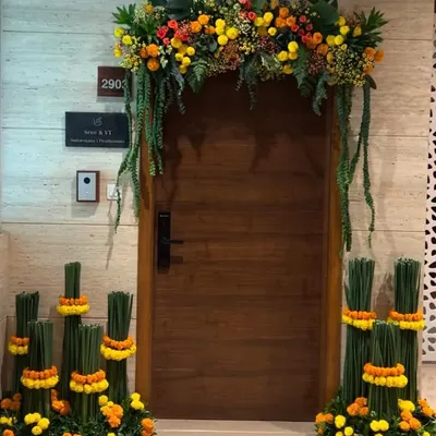To create a warm and festive welcome, we designed this entrance decor using vibrant marigolds and lush greenery. The arrangement frames the doorway, with unique vertical floral stands on either side adding a modern touch to a traditional element.