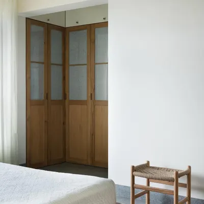These corner wardrobe doors are crafted from light oak with frosted glass panels. I designed them to provide visual softness and texture in the master bedroom, hiding storage without adding visual weight.
