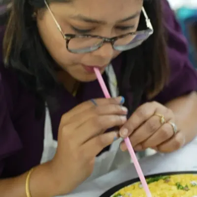 A close-up shot of a participant using a straw to create delicate wave effects in her resin beach art. This simple technique helps make realistic, lacy sea foam on the shore.