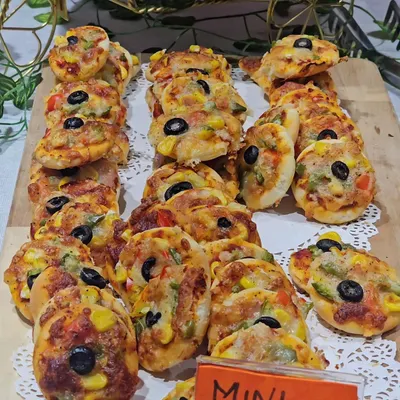 A platter of delicious mini vegetable pizzas, topped with corn, olives, and bell peppers. These bite-sized treats are perfect for little hands and are always a party favorite.