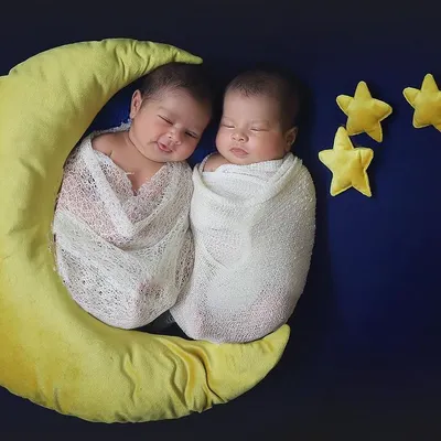 Two little stars sleeping on a crescent moon. This celestial theme is one of my favorites for twin newborn photography. The simple white wraps and dark blue background make the babies the shining center of attention.
