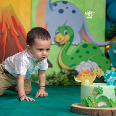 That moment of curiosity just before the fun begins! This little one is eyeing his dinosaur-themed cake, ready for his first taste of birthday sweetness.