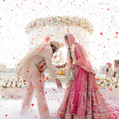 A whirlwind of love and petals. I styled this moment to feel like a dream, with a custom-coordinated pastel palette for the couple's outfits and a cloud of smoke to create an ethereal, romantic atmosphere for their varmala ceremony.
