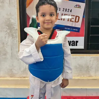 Ready to fight. This young student shows his fighting stance, fully equipped with a chest guard for safe practice. We ensure all our little warriors feel confident and protected.