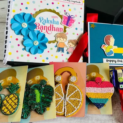 A complete Rakhi celebration in one box! This hamper includes a custom scrapbook, a variety of our popular handmade beaded earrings, a greeting card, and chocolates. It’s the perfect surprise for a sister.