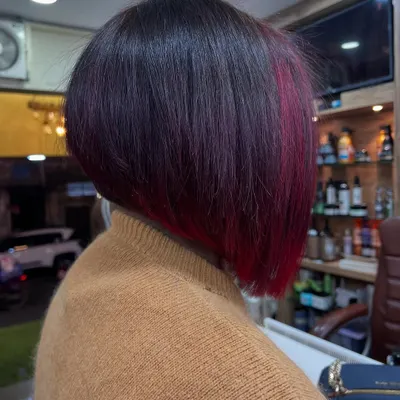A sharp, angled bob with a secret splash of color. This look features a vibrant magenta panel underneath, adding an edgy and surprising element to a classic cut.