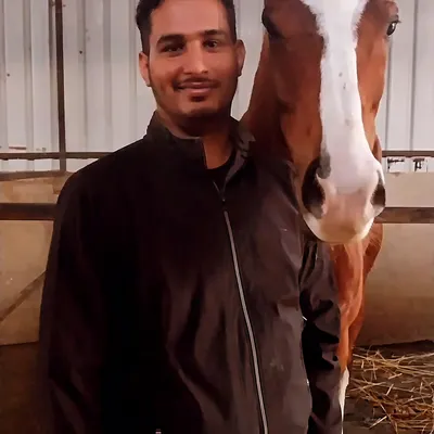 A member of our team shares a moment with Vikrant, one of our most loved horses, inside the stable.