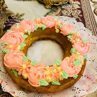 A beautiful ribbon bundt cake decorated with a wreath of delicate pink buttercream roses and sprinkles. It's perfect as a centerpiece for a tea party.