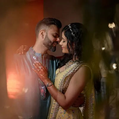 An intimate couple portrait shot through foreground elements, creating a dreamy, romantic feel. The warm lighting and close embrace make this a very powerful image.
