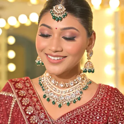A perfect close-up of a classic Kundan set featuring green bead drops. This image clearly shows the intricate setting of the stones in the necklace, earrings, and maang tikka.