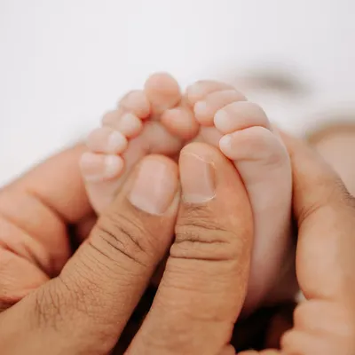 A parent's hands gently holding their newborn's tiny feet. This macro shot is a powerful reminder of how small and precious new life is.