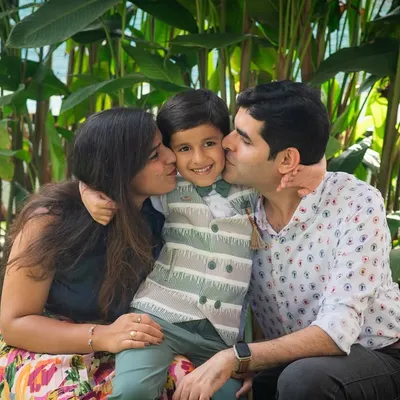There's nothing sweeter than kisses from mom and dad. This candid family portrait is overflowing with love and affection, captured during an outdoor birthday celebration.
