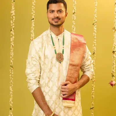 A solo shot from the C. Krishniah Chetty campaign, modeling a classic cream kurta with an emerald green necklace. The look is simple, elegant, and timeless.