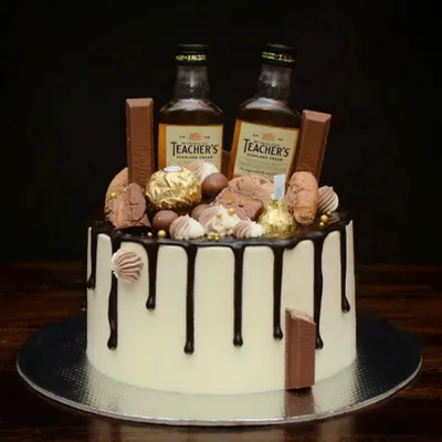 This is my signature loaded drip cake, perfect for a milestone birthday. It features a rich chocolate drip, and is topped with miniature whiskey bottles, Ferrero Rocher, KitKats, and other chocolatey treats.