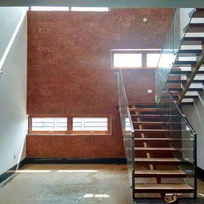 This spacious double-height courtyard is the heart of one of our residential projects in Bengaluru. The combination of a laterite-clad wall, a floating staircase with glass railings, and circular skylights creates a dynamic play of light and natural texture.