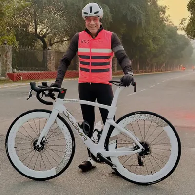 A proud rider with his stunning white Pinarello Dogma, a top tier racing bike known for its performance. We appreciate and celebrate high quality cycling equipment.