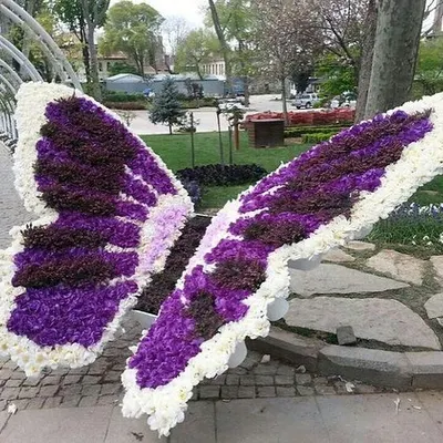 A large, custom-made butterfly sculpture created entirely from artificial flowers. This type of artistic installation is perfect for public gardens, events, or as a unique photo opportunity.