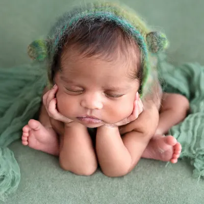 The adorable "froggy pose" is a client favorite, and it's created with the utmost care. This is a composite image, meaning the baby is supported by hands at all times to ensure complete safety while achieving this sweet, curled-up look.