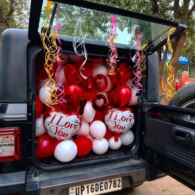 If you want a surprise that's different, I can do a car boot decoration. I fill the car boot with balloons and ribbons, like this red and white 'I Love You' theme, so you can reveal the surprise anywhere you like.