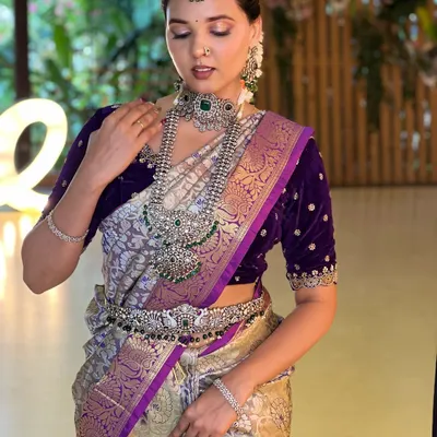 This grand silver-finish necklace set with green stones makes a powerful statement. Paired with a deep purple velvet blouse, it creates a look of pure royalty and modern elegance.